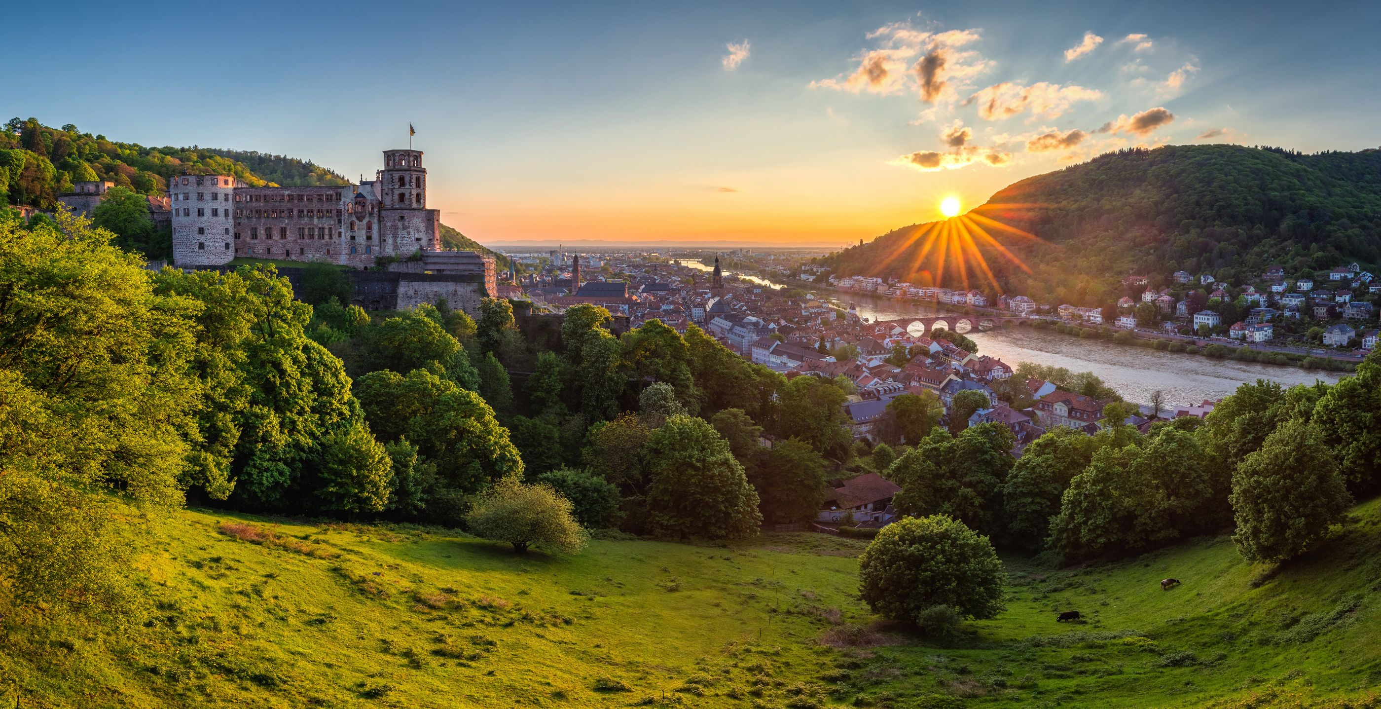 Heidelberger Schloss über der Altstadt mit Neckar und Alter Brücke bei Sonnenuntergang